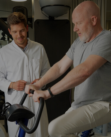 Physical therapist assisting an older man with arm exercises in a gym setting